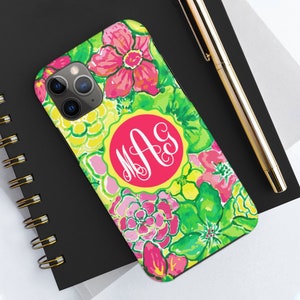 Pu&ograve; includere: Una custodia per telefono floreale verde, rosa e gialla con un monogramma circolare rosa con le lettere "M.A.G."