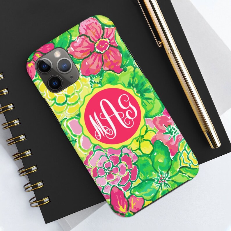 Pu&ograve; includere: Una custodia per telefono floreale verde, rosa e gialla con un monogramma circolare rosa con le lettere "M.A.G."