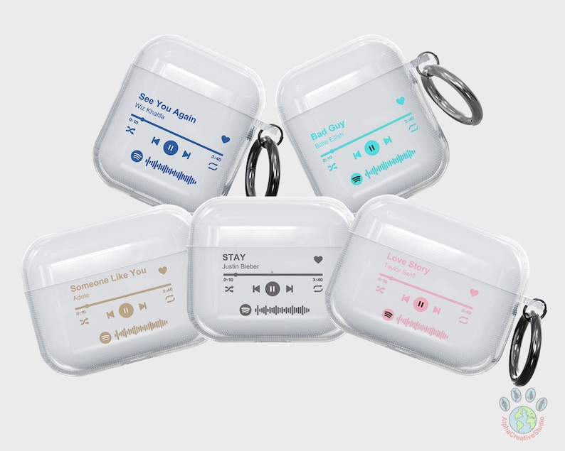 May include: Five clear plastic cases for AirPods with different song titles and artist names printed on them. The cases are all white and have a black ring attached to them. The song titles are "See You Again", "Bad Guy", "Someone Like You", "STAY", and "Love Story".