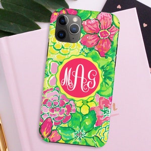 Pu&ograve; includere: Una custodia per telefono floreale rosa, verde e gialla con un monogramma delle lettere "MAG" in un cerchio bianco su sfondo rosa.