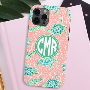 May include: A pink phone case with a white and green sea turtle pattern. The case has a green monogram "CMR" in the center.