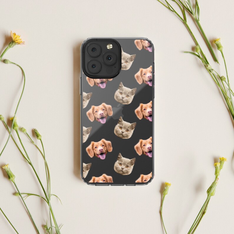 May include: A clear phone case with a repeating pattern of dog and cat faces. The case is black and the faces are in shades of brown, white, and gray.