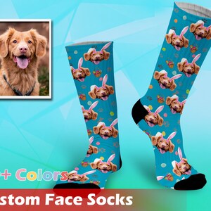 May include: A pair of blue custom face socks with a dog's face printed on them. The socks have a light blue background with white paw prints and pink bunny ears. The dog's face is surrounded by a pink bunny ear headband. The socks are available in 20+ colours. Custom Face Socks.