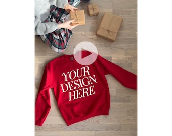 May include: Red sweatshirt with the text "YOUR DESIGN HERE" in white on the front. The sweatshirt is lying on a wooden floor.