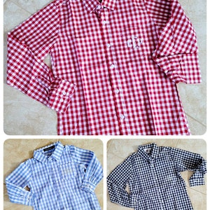 May include: Three long-sleeved button-down shirts in different colors and patterns. The first shirt is red and white gingham, the second is blue and white gingham, and the third is black and white gingham. Each shirt has a pocket on the left chest with a monogram.