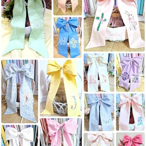May include: A collage of decorative bows in various colors, including light green, pink, blue, and yellow. Some bows feature embroidered designs such as initials, crosses, and bunnies. The bows are likely used for gift wrapping or decorative purposes.