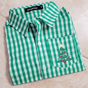 May include: Green and white gingham button-down shirt with a small embroidered Christmas tree in the pocket. The shirt has the text "Spring & Gege" on the label.