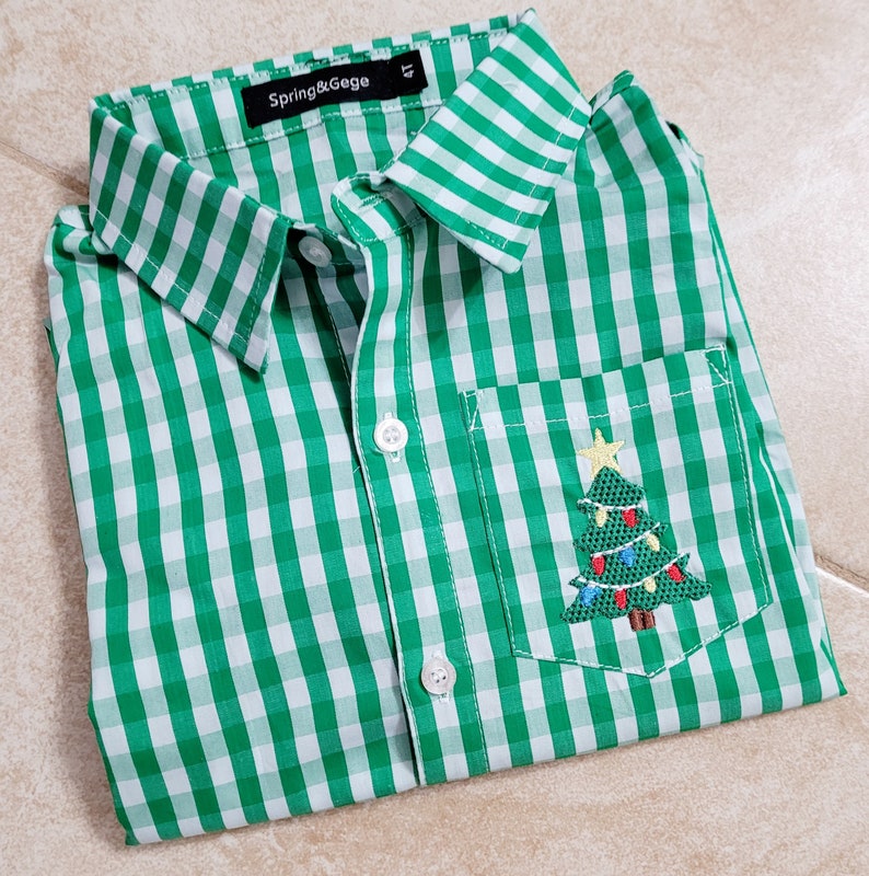May include: Green and white gingham button-down shirt with a small embroidered Christmas tree in the pocket. The shirt has the text "Spring & Gege" on the label.