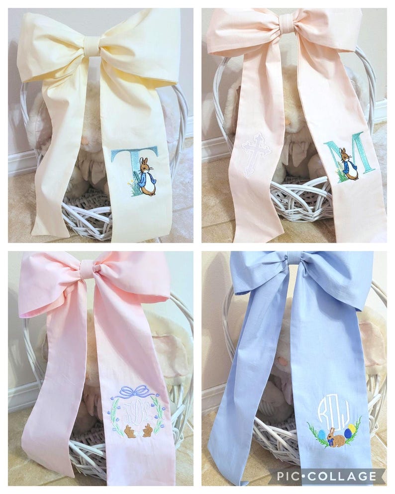 May include: A collage of four decorative bows in pastel colors: cream, pink, and blue. Each bow features a long, embroidered ribbon with a Peter Rabbit design and a letter or monogram. The bows are tied on white wicker baskets.