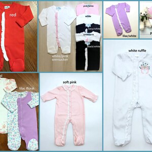 May include: A collection of long-sleeved footed infant sleepers in various colors including red, white, pink, lilac, navy, and black. Several feature a vertical ruffle detail along the front closure, while others display floral patterns or embroidery.