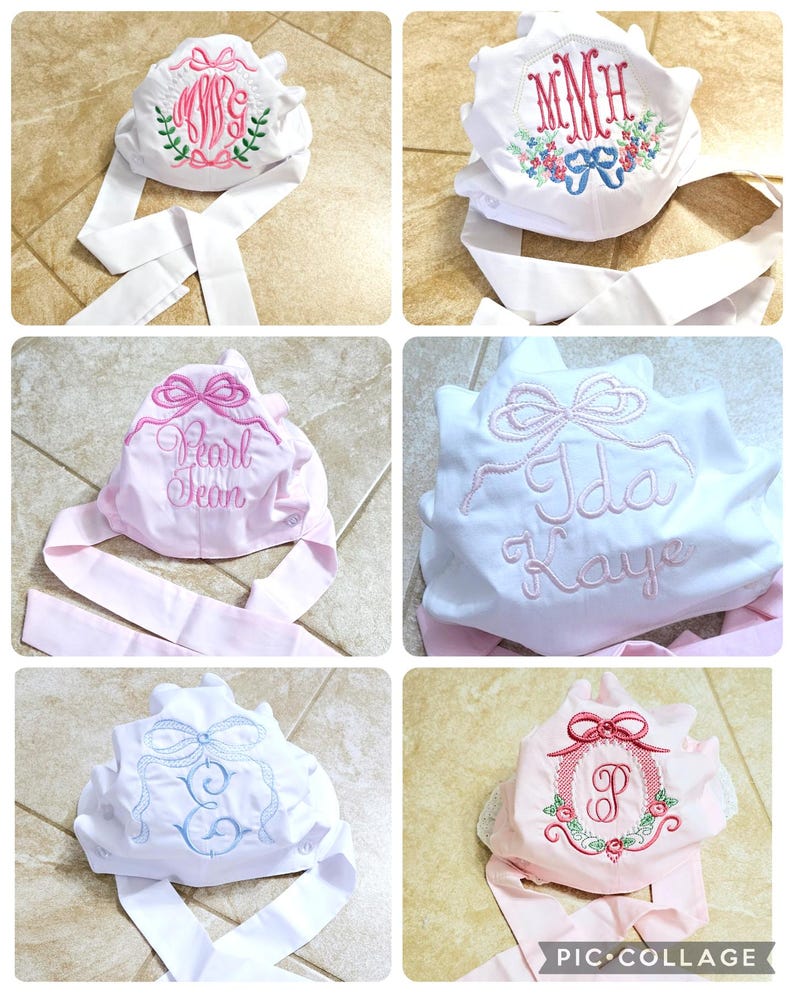May include: Four white fabric bonnets with pink and blue ribbon ties. Each bonnet is embroidered with a different design, including a monogram, a name, and a bow. The bonnets are displayed on a tiled surface.
