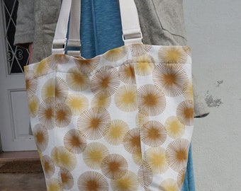 May include: A white tote bag with brown and yellow sunburst designs. The bag has two white straps.