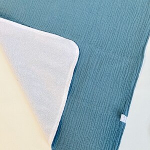 May include: A soft, blue and white reversible baby blanket. One side is a textured blue fabric and the other side is a white terry cloth.