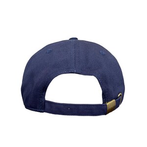 May include: Navy blue baseball cap with a curved brim and adjustable strap. The cap features a brass-colored metal buckle on the back for size adjustment. The cap is made of a durable fabric.