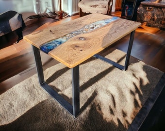May include: A wooden coffee table with a black metal frame. The table top has a river of blue epoxy resin with white and brown accents.