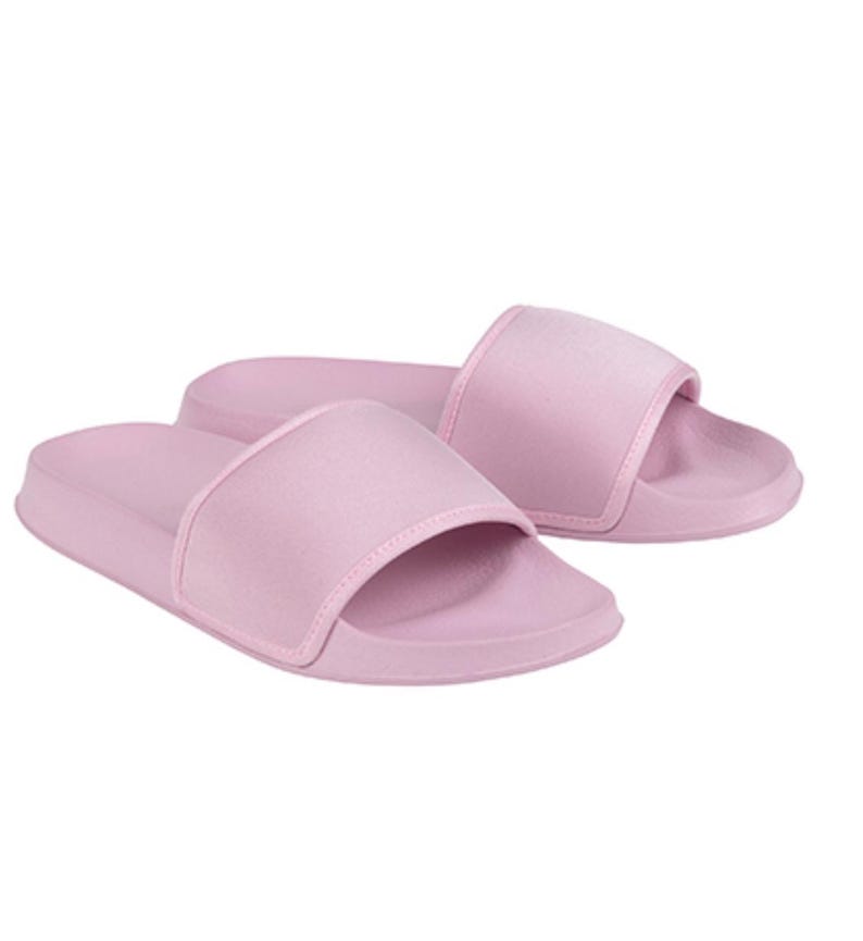 May include: A pair of pink slide sandals. The sandals have a wide strap across the top of the foot.