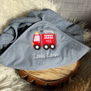Könnte beinhalten: Ein graues Kapuzenhandtuch mit einem roten Feuerwehrauto, das darauf gestickt ist. Das Feuerwehrauto hat die Nummer 112 an der Seite. Das Handtuch ist mit dem Namen "Louis Lenn" personalisiert.