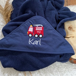 May include: A navy blue hooded towel with a red embroidered fire truck and the name "Karl" on it.