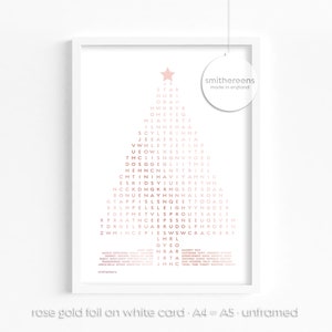 Puede incluir: Una impresi&oacute;n enmarcada en blanco con un dise&ntilde;o de &aacute;rbol de Navidad en l&aacute;mina de oro rosa. El &aacute;rbol est&aacute; formado por las palabras "STAR", "HUB", "ORAV", "HWK", "BYE", "OME", "YID", "NLAYT", "INHE", "SCYLTRIN", "JEEAERLAJA", "VWHLEYSETINF", "UEQWLXSSIYTR", "TMCIISNONVYDED", "DOSGGEGLIITHSE", "HEHNCNENTTRIEL", "CMTINIHAVIYAHNIC", "ESKIDSY", "ETWH", "NCCKOHG", "DFSDAA", "BONUE", "GTA", "ALKORN", "ETTODAST", "YYNGDER", "AELI", "R", "TORO", "ZWHINCEP", "HROBIN", "SWCRACKERF", "LMRL", "GYEO", "INR", "IRRA", "IHHC". La impresi&oacute;n tambi&eacute;n incluye el texto "smithereens made in england".