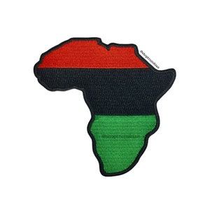 May include: A patch in the shape of the African continent, featuring horizontal stripes of red, black, and green. The patch has a black border and is set against a white background. The text "@shoptrunubian" is visible.