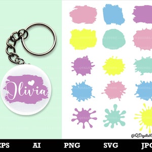 May include: A pink, blue, and purple paint splatter design with the name Olivia in white text. The design is on a white circle attached to a silver key chain.