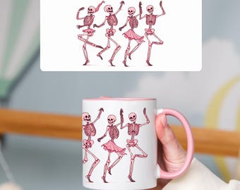 Könnte beinhalten: Weiße Keramiktasse mit rosafarbenem Rand und Henkel. Die Tasse zeigt ein Design mit fünf rosa Skeletten, die in einer Reihe tanzen.