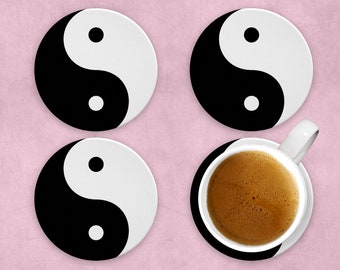 Könnte beinhalten: Vier schwarze und weiße Yin-Yang-Untersetzer mit einer Tasse Kaffee auf einem der Untersetzer.
