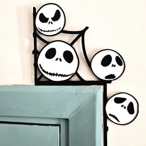 May include: Four black and white Jack Skellington faces are attached to a black metal corner shelf. The shelf is mounted on a light blue wall.