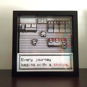Può includere: Una stampa di pixel art incorniciata di una scena della serie di videogiochi Pokemon. La stampa presenta un personaggio in piedi di fronte a un negozio con il testo "Every journey begins with a choice."