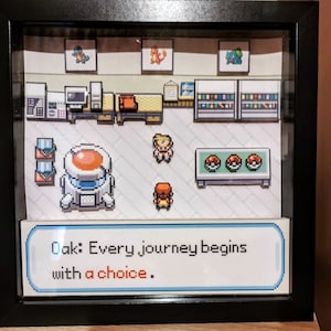 Può includere: Un diorama di pixel art incorniciato che rappresenta una scena della serie di videogiochi Pokémon. Il diorama presenta un personaggio in piedi di fronte a un tavolo con tre Poké Ball. Il testo "Oak: Ogni viaggio inizia con una scelta." è visualizzato nella parte inferiore del diorama.
