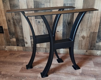 May include: Two black metal table legs with a curved design. The legs are made of sturdy metal and have a black powder coat finish.