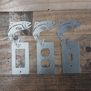 May include: Three metal light switch and outlet covers with a fish design. The covers are silver with a textured finish. The fish are in a jumping position.