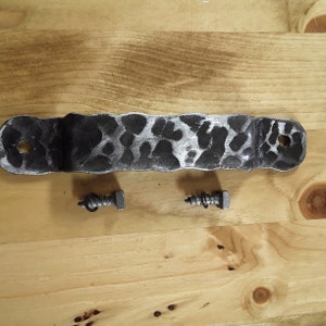 May include: A black metal door handle with a textured surface and two silver screws.