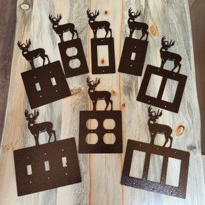 May include: A set of eight decorative light switch covers featuring a deer silhouette design. The covers are made of metal and have a brown finish. The covers are available in a variety of configurations, including single, double, and triple switch covers.