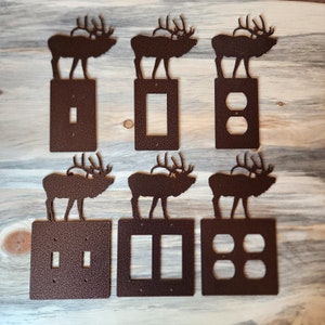 May include: Six brown metal light switch covers with an elk silhouette on each. The covers are for single, double, and triple switches.