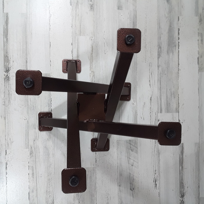 Op de afbeelding: Een bruine metalen tafelvoet met een geometrisch ontwerp. De voet heeft een centrale vierkante steun met zes rechthoekige armen die naar buiten uitsteken, elk eindigend in een vierkante voet. De armen zijn verbonden met bouten.