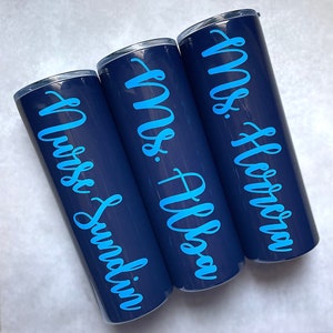 20 oz midnight stainless steel tumbler with custom solid sky blue decal. Tumbler includes name and apple design on opposite side of tumbler. Tumblers are good for HOT or COLD liquids and can be used with or without straw that is provided.