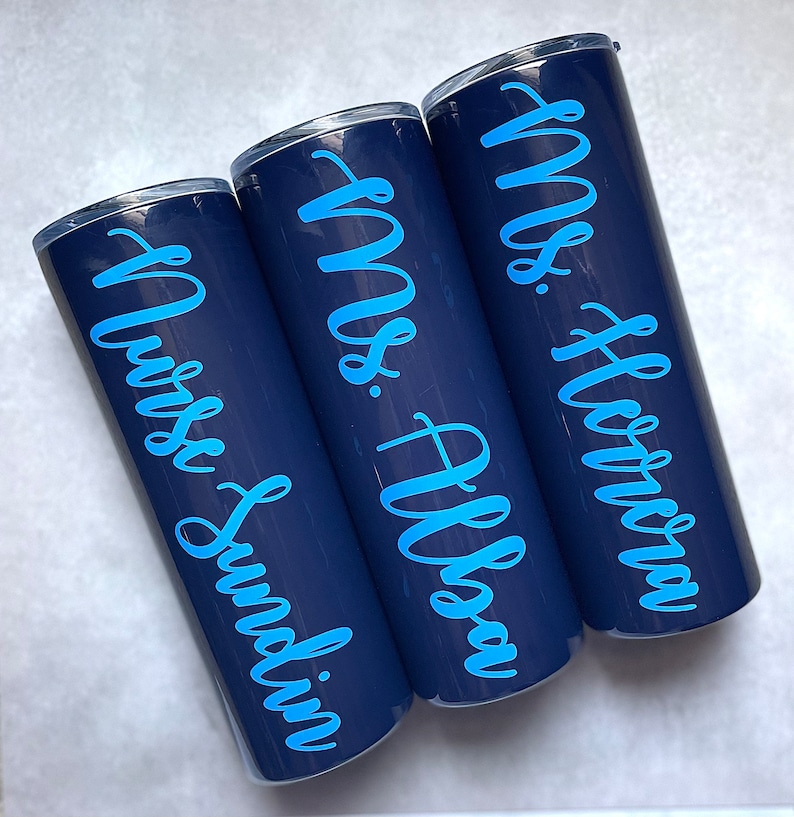 20 oz midnight stainless steel tumbler with custom solid sky blue decal. Tumbler includes name and apple design on opposite side of tumbler. Tumblers are good for HOT or COLD liquids and can be used with or without straw that is provided.