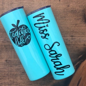 20 oz light blue stainless steel tumbler with custom solid black decal. Tumbler includes name and apple design on opposite side of tumbler. Tumblers are good for HOT or COLD liquids and can be used with or without straw that is provided.