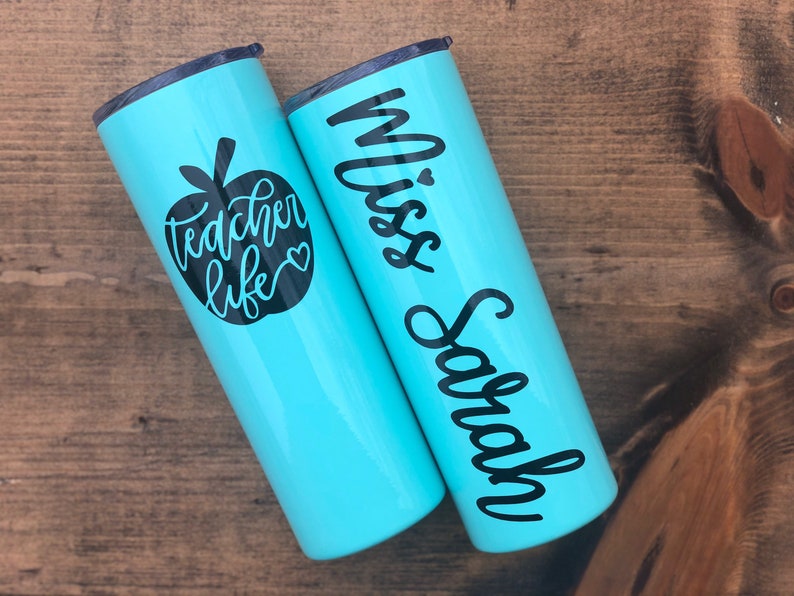 20 oz light blue stainless steel tumbler with custom solid black decal. Tumbler includes name and apple design on opposite side of tumbler. Tumblers are good for HOT or COLD liquids and can be used with or without straw that is provided.