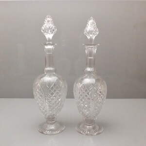 May include: Two clear glass decanters with a diamond pattern and a pineapple-shaped stopper.