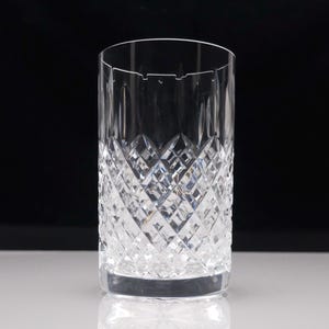 Peut inclure: Un verre highball en cristal transparent présentant un motif détaillé en losanges taillés sur les deux tiers inférieurs du corps, se transformant en cannelures verticales près du bord circulaire lisse, créant une surface texturée.