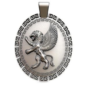 Puede incluir: Pendiente de plata con un león alado y un borde de llave griega. El león está representado de pie, con las alas extendidas.