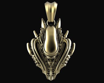 May include: A gold-colored pendant featuring a detailed alien head design. The pendant has a textured, intricate design with a rounded head and a detailed face.