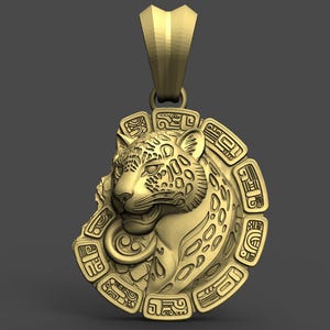 Puede incluir: Colgante dorado con la cabeza detallada de un jaguar con manchas y un marco circular con símbolos grabados. El colgante tiene un lazo para una cadena y una fianza texturizada.