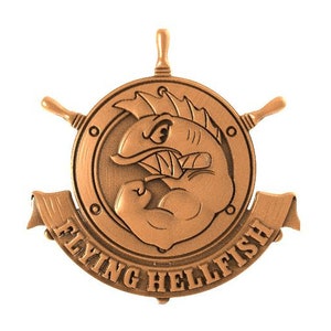 Peut inclure: Un emblème en métal de couleur bronze sur le thème nautique. Il représente un poisson de dessin animé avec un bras musclé, un gouvernail de navire et une bannière qui dit "Flying Hellfish".