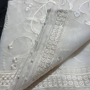 May include: Two sheer fabric scarves, one black and one white, with delicate floral embroidery. The white scarf has a border of small circles.