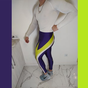 Könnte beinhalten: Lila und gelbe Leggings mit weißen Akzenten. Die Leggings sind aus einem glänzenden, dehnbaren Material.