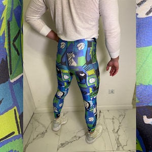 Könnte beinhalten: Leggings mit einem lebendigen abstrakten Design in Blau-, Grün- und Schwarztönen. Die Leggings weisen ein sich wiederholendes Muster aus geometrischen Formen und künstlerischen Elementen auf. Die Person trägt ein weißes Langarmshirt und weiße Turnschuhe.