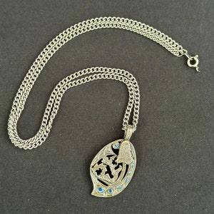 May include: A silver chain necklace with a pendant shaped like a leaf with blue accents. The pendant has a detailed design and is attached to a silver chain.